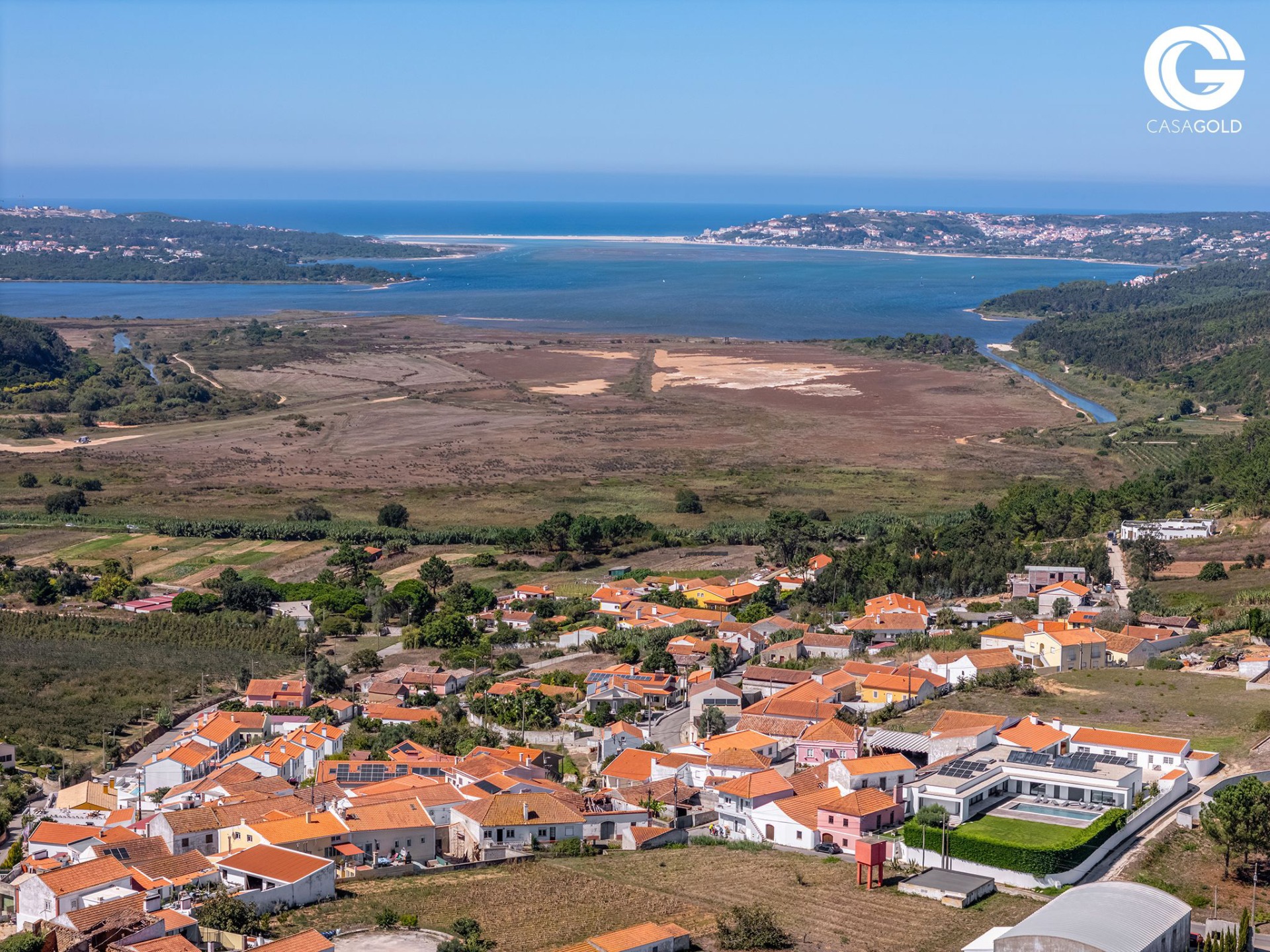 Panoramic view of Óbidos Lagoon over the rooftops of Arelho on a clear, blue-sky day